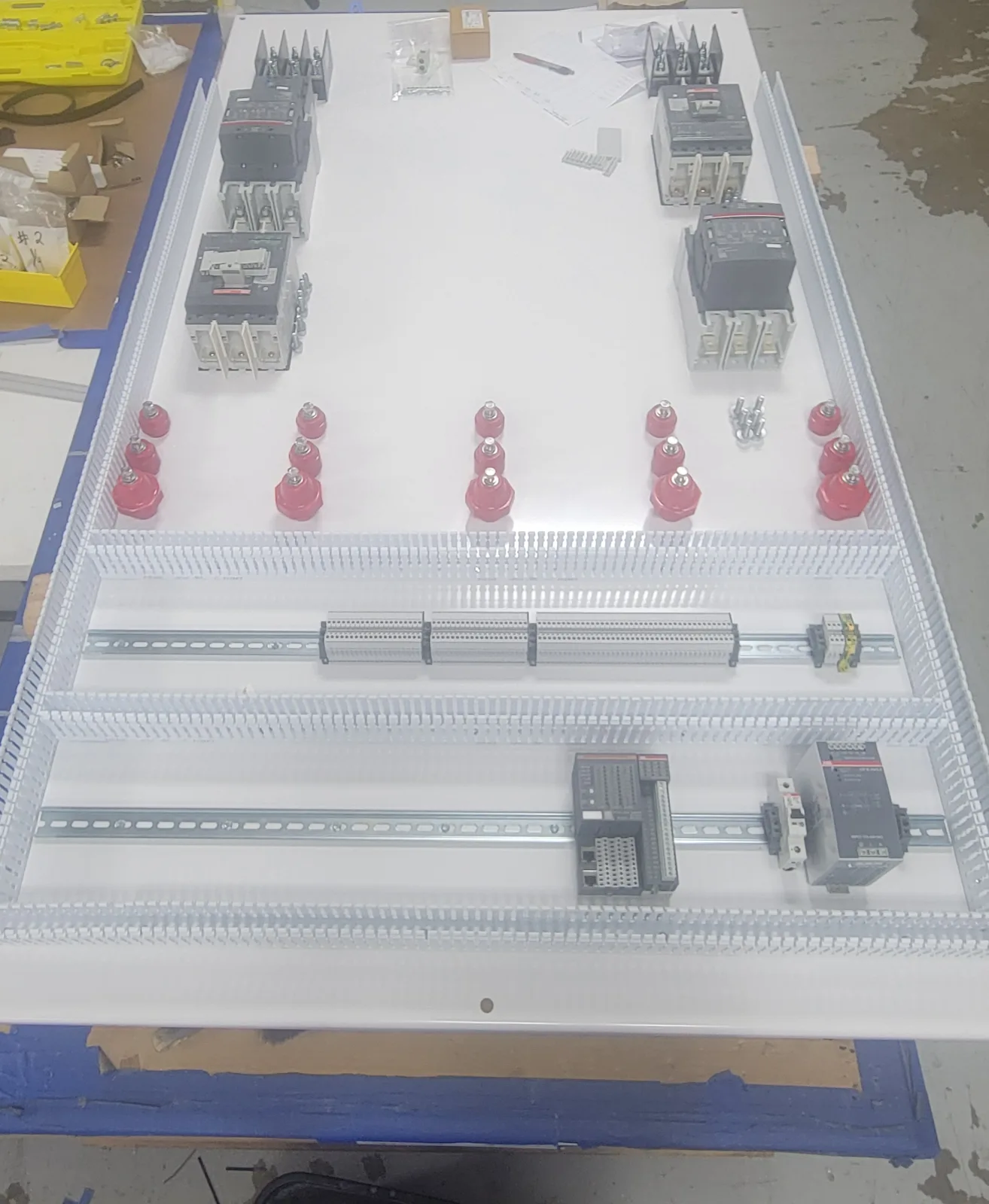 Panel back-plate in build on the shop bench: breakers and contactors mounted, wire duct and DIN rail laid out